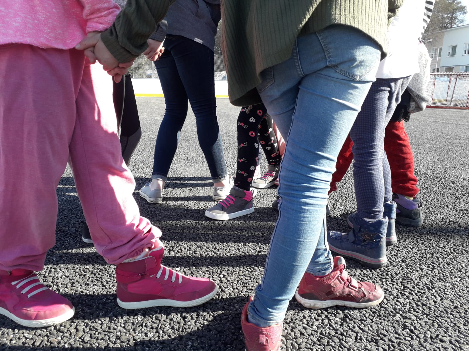 Lasten jalkoja asfaltilla pihaleikissä.