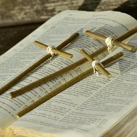 Raamatun päällä kolme tikuista tehtyä ristiä.